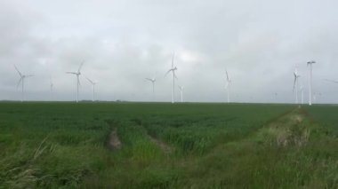 Gökyüzü bulutlu rüzgâr parkındaki alternatif enerji değirmenlerine panoramik bakış.