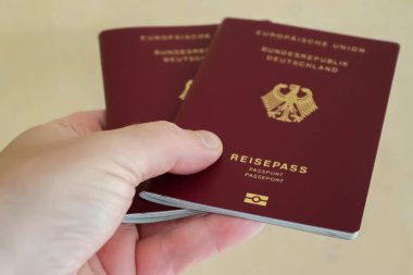 Bir erkek pasaport kontrolü için iki Alman pasaportu tutuyor.