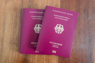 Pasaport kontrolü için tahta arka planda iki Alman pasaportu.