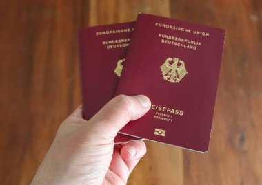 Bir erkek pasaport kontrolü için iki Alman pasaportu tutuyor.