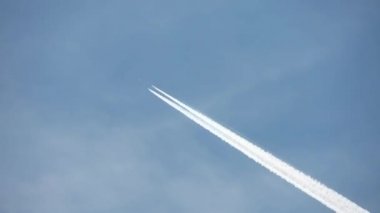 Gökyüzünde yükseklerde uçan jet uçağı açık mavi gökyüzünde kontrastlar bırakır..