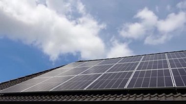 Time lapse of clouds and sky on solar panels producing clean energy on a roof of a residential house.