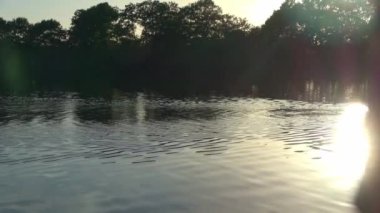 Beautiful view at a lake with the light of the sunset on the water surface.