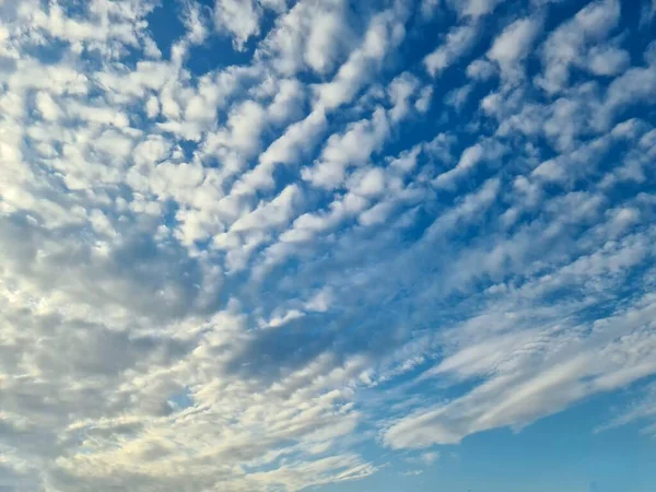 飞机在蓝天中的几片美丽的云彩之间凝结着痕迹 — 图库照片