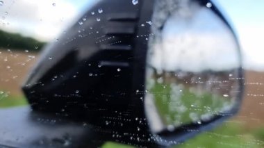 Dikiz aynasının önünde yüksek hızda hareket eden yağmur damlaları..