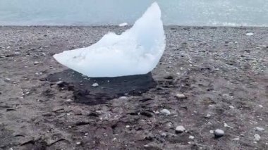 İzlanda 'da elmas plajı. Mavi buzdağları eriyor. Siyah kum ve buzlar güneş ışığıyla parlıyor..