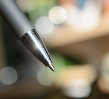 Ballpoint silver pen close-up on a blurred background. Concept - sign documents