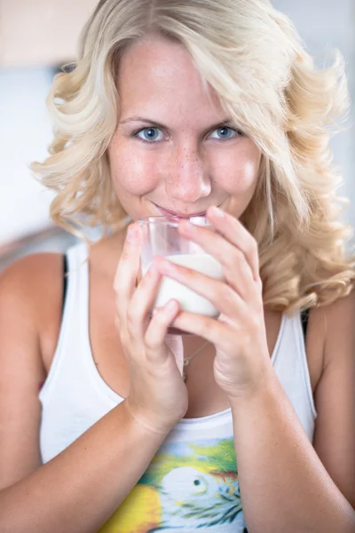 Young girl drinks a glass of milk in kitchen — Stock Photo, Image
