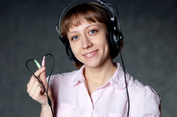 Νεαρό κορίτσι με ακουστικά, κρατώντας δύο καλώδια — Φωτογραφία Αρχείου