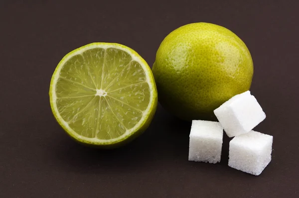 Lime and sugar cubes on a brown background — Stock Photo, Image