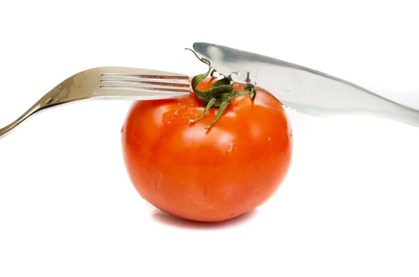 Червоний стиглий помідор з виделкою і ножем — стокове фото