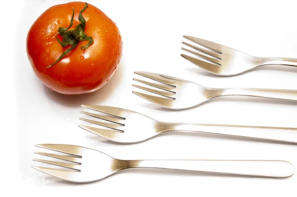 Tenedores de mesa Perspectiva en una fila y un tomate rojo —  Fotos de Stock