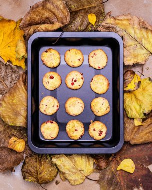 Sonbahar yemek kompozisyonu, pişirme tepsisi ve sonbahar kuru yapraklı ev yapımı kızılcık kurabiyeleri. Ulusal İskandinav hamur işleri. Doğal sağlıklı fırın ürünleri