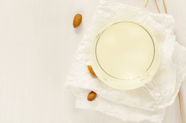 Badem sütü. Vejetaryen besin bileşimi. Bir bardak bitki sütüyle. Beyaz arka planda badem ve fotokopi alanı. Sütsüz ürün