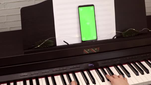 子供が演奏する電子ピアノの緑の画面を持つスマートフォン オンラインピアノレッスン オンライン音楽の休日コンサート モバイル音楽アプリ用のモックアップ オンライン音楽教育 スローモーション — ストック動画