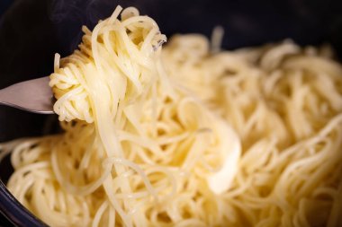 Geleneksel spagetti. Tavada sıcak makarna ve siyah arka planda bir parça tereyağı ile yemek kompozisyonu. Akdeniz, İtalyan yemekleri, basit yemekler.
