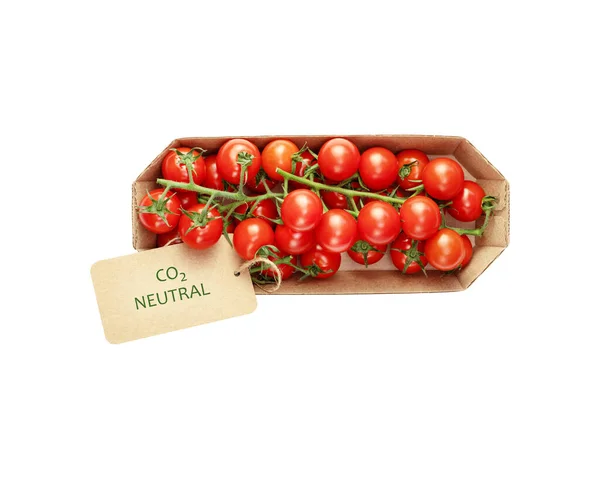 Isolated organic cherry tomatoes in an eco friendly craft package with a label with the inscription carbon neutral on a white background. Season lockal vegetables with carbon labeling. Flat lay