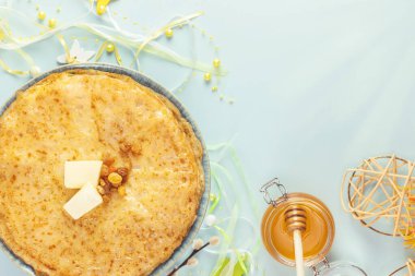 Ev yapımı krep yığını, ballı kavanoz ve güneş ışınları ve fotokopi alanı olan mavi bir arka plan. Rus ulusal yemeği. Maslenitsa Tatili