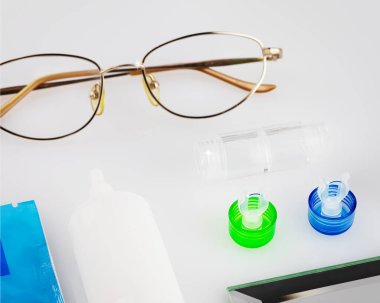 Lensleri, konteynırları, gözlükleri ve göz damlalarını beyaz bir masaya bırakın. Kontak, gece lensleri ve onların bakımının düzgün kullanımı. Eyecare