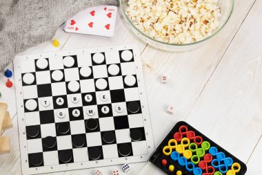 Masa oyunları. Dama, bulmaca, kart, domino, tahta zeminde bir kase patlamış mısır ve battaniyeyle Jenga. Eğitim oyunları ve aile eğlencesi kavramı