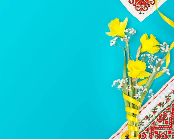 Ukrayna tatil kartı. Bir buket sarı nergis ulusal işlemeli peçeteler ve mavi arka planda fotokopi alanı. Ukrayna bayrağının renklerinin çiçek bileşimi
