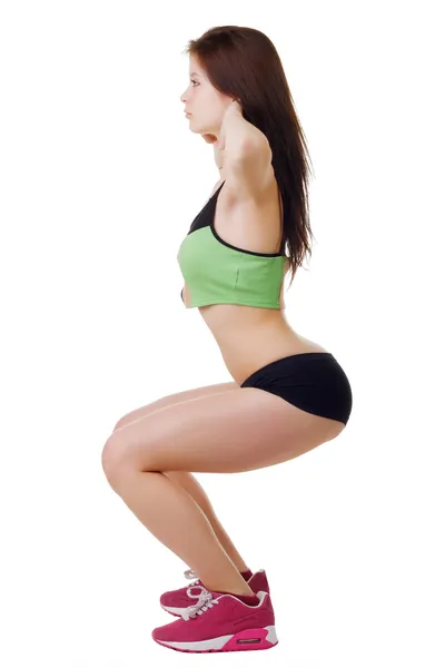 Jong meisje in korte broek en een shirt sport voert squats. — Stockfoto