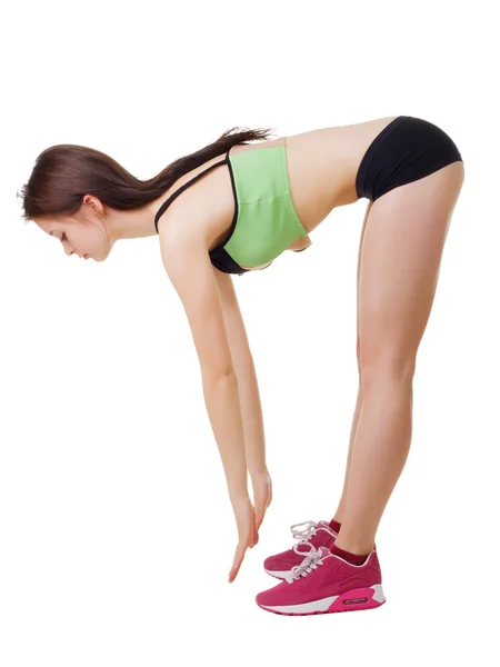 Young girl in short shorts and a sports shirt performs slopes torso. — Stock Photo, Image