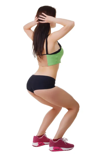 Young girl in short shorts and a sports shirt performs squats. Stock Image