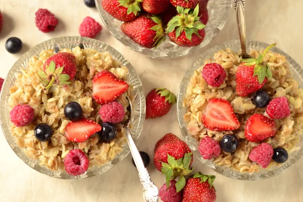 Haferbrei mit Körnern, frischen Beeren in einer Glasschüssel und Tee zum Frühstück — Stockfoto