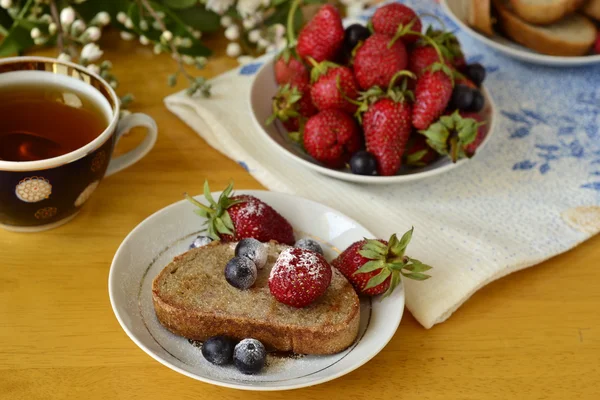 Rozs pirítós, friss bogyós gyümölcsök a porcukorral és a tea a reggeli — Stock Fotó