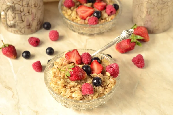 Haferbrei mit Körnern, frischen Beeren in einer Glasschüssel und Tee zum Frühstück — Stockfoto