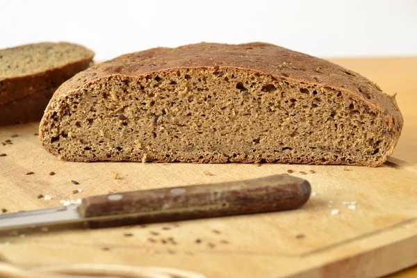 Homemade olive rye bread with flax seeds on a wooden board — Stock Photo, Image