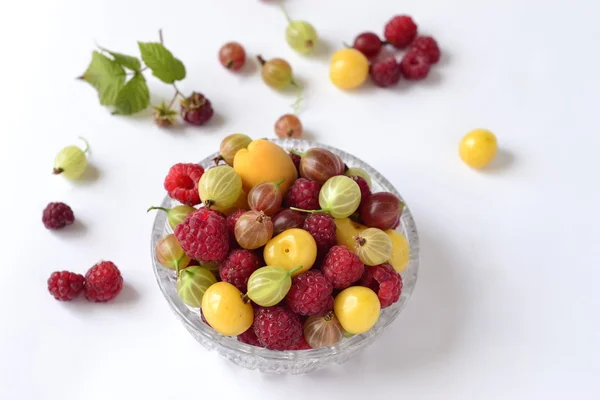 Berries in a glass bowl on a white background (raspberry, cherry, gooseberry) — Stock Photo, Image
