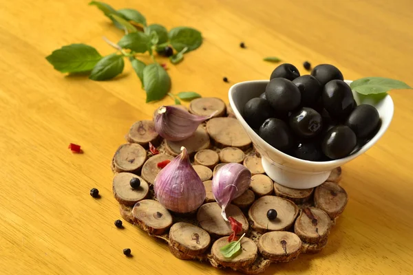 Оливки в белой чаше на деревянном столе — стоковое фото