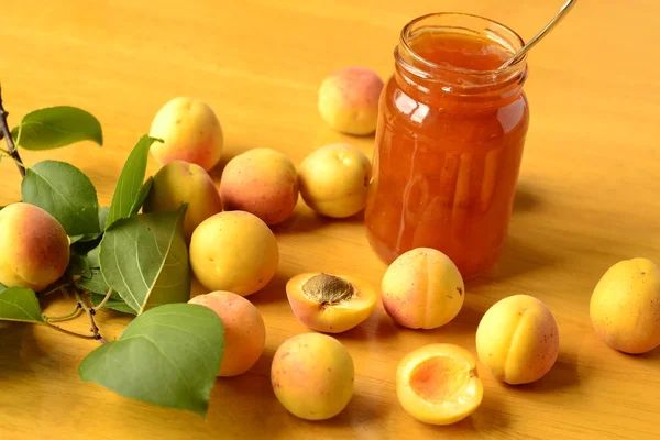 Абрикосовое варенье и свежие абрикосы на деревянном столе — стоковое фото