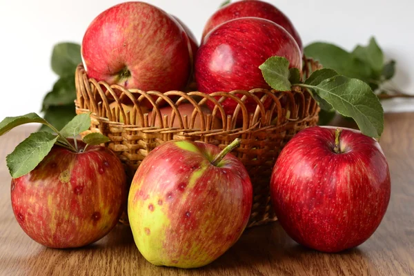 Red apples with leaves in a basket on the table — Stock Photo, Image