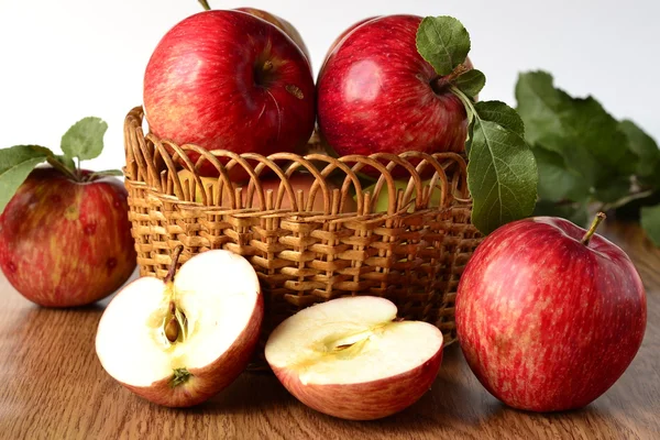 Red apples with leaves in a basket on the table — Stock Photo, Image