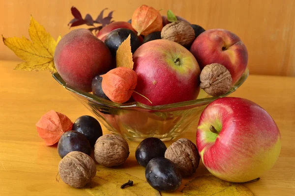 Autumn fruit in a vase on a wooden table — Stock Photo, Image