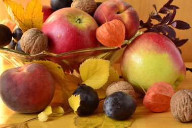 ahşap bir masa üzerinde bir vazoda sonbahar meyve