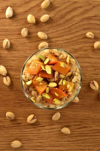 Oatmeal porridge with persimmons, pistachios and honey — Stock Photo, Image