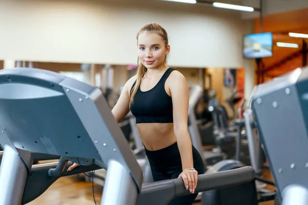 Eine junge Frau übt sich im Fitnesstraining am Gymnasium. Eine Frau auf einem Laufband. — Stockfoto