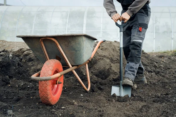 Trabalhando com ferramentas de jardim, pá e carrinho de mão no local de uma casa de campo. Preparação para trabalhos de construção. — Fotografia de Stock