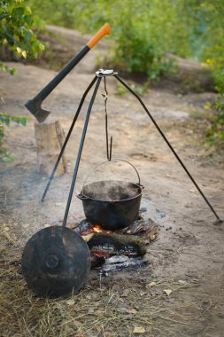 Bir kamp tenceresi, bir balta, yakacak odun ve şenlik ateşi. Vahşi kamplarda kamp ateşinde yemek hazırlamak, doğada dinlenmek..