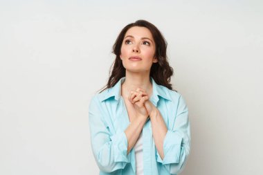 Esmer kadın dua ederken ellerini kavuşturdu. Bir kadın Tanrı 'dan yardım ister.