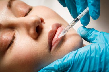 Bir kadın kozmetoloji kliniğinde dudak şekli düzeltmesi yapıyor. Dudak aşısı, dudak büyütme..