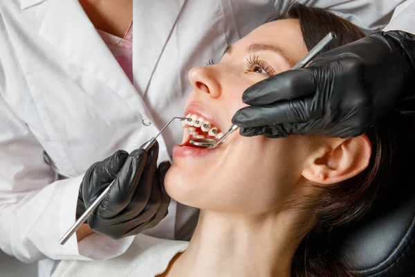 A young woman with metal braces is being examined by an orthodontist. Correction of the bite of teeth in the dental clinic. Concept of healthy teeth. — Stockfoto