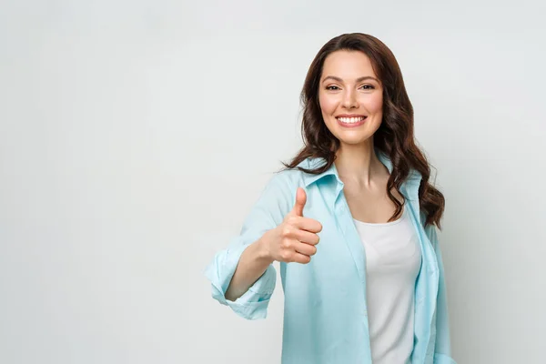 Giovane donna attraente, bruna, con un sorriso raggiante, dando un pollice verso l'alto gesto di approvazione e successo. — Foto Stock