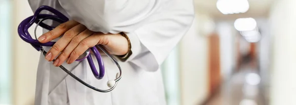 Doctor holding a stethoscope. on the background of blurred hospital corridor. — Stockfoto