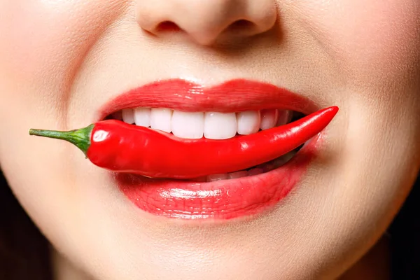 Kvinna med chili röd paprika isolerad en blå bakgrund. Sexiga kvinnliga läppar. Het förförisk flicka. Stockfoto