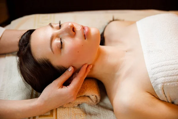 Jonge vrouw in een spa salon. Gezichtsmassage. — Stockfoto